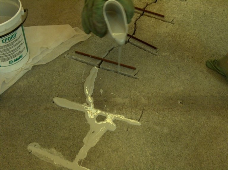 A crack being repaired with stitching bars and epoxy resin during floor preparation