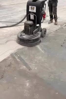 A walk-behind diamond grinder preparing a concrete floor for resin flooring